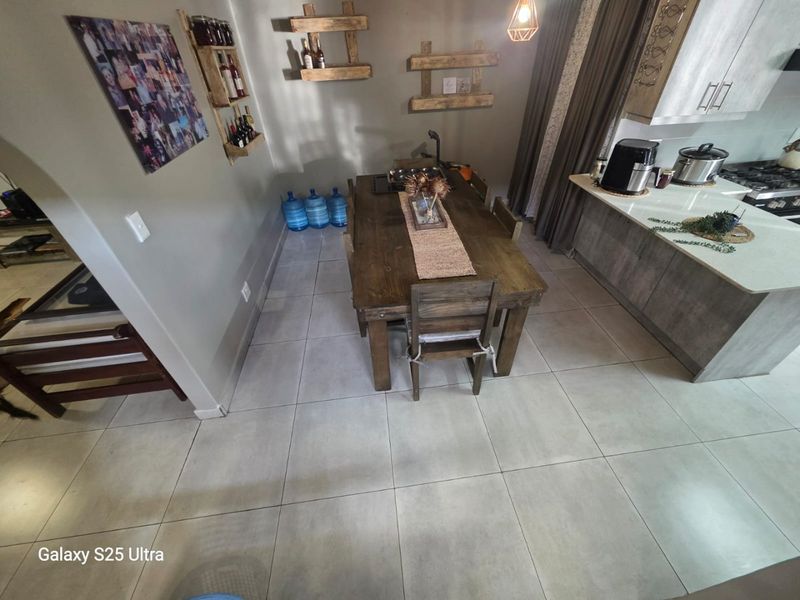 Open-plan kitchen and dining area featuring modern cabinetry, a central island with a gas cooktop, and neutral tiled flooring throughout.