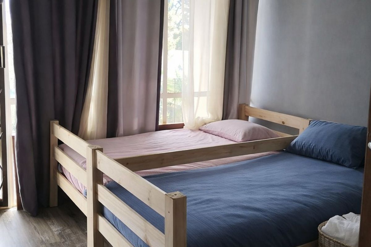 A bedroom featuring wood-look laminate flooring, recessed ceiling lighting, and a large window with floor-to-ceiling curtains.