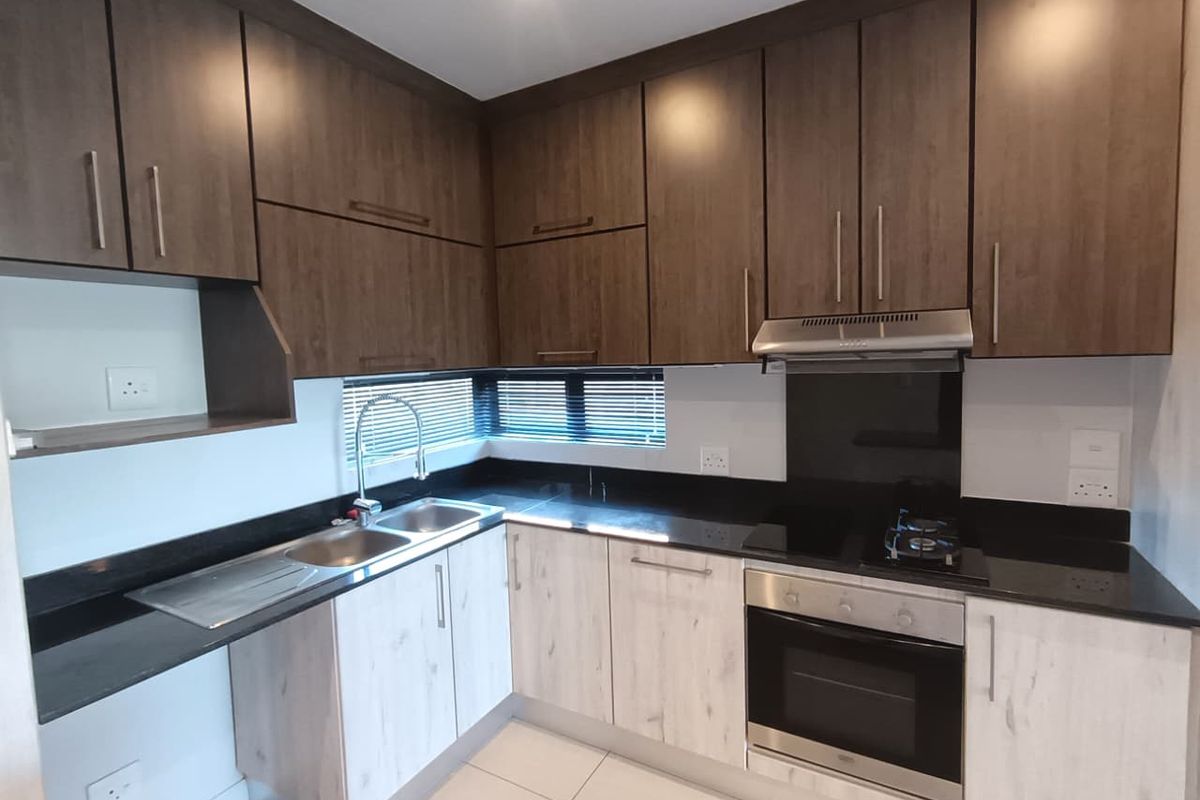 Modern kitchen featuring two-tone cabinetry, granite countertops, integrated oven, hob, and extractor fan with a clean, functional layout.