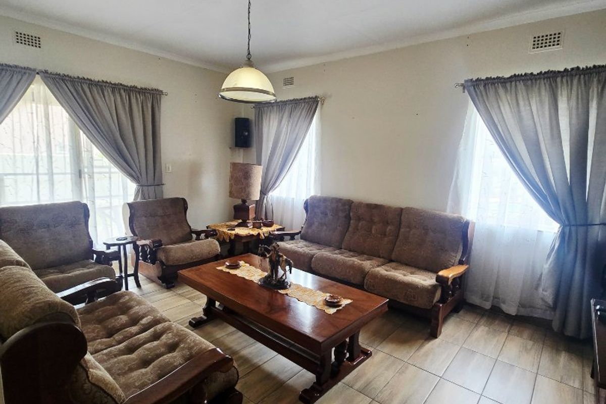 A living room featuring tiled flooring, neutral walls, and natural light from multiple windows, providing a functional and comfortable living space.