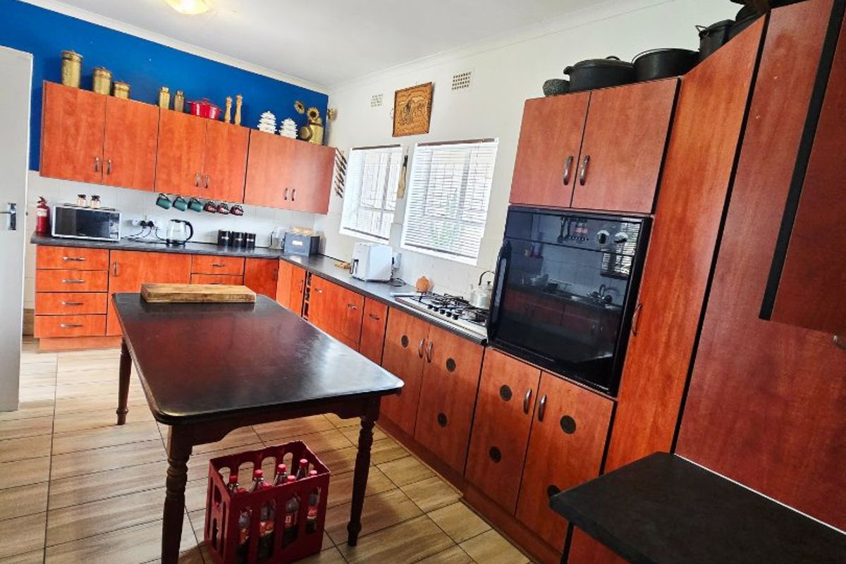 A functional kitchen featuring wood-finish cabinetry, dark countertops, a built-in oven, gas hob, and tiled flooring.