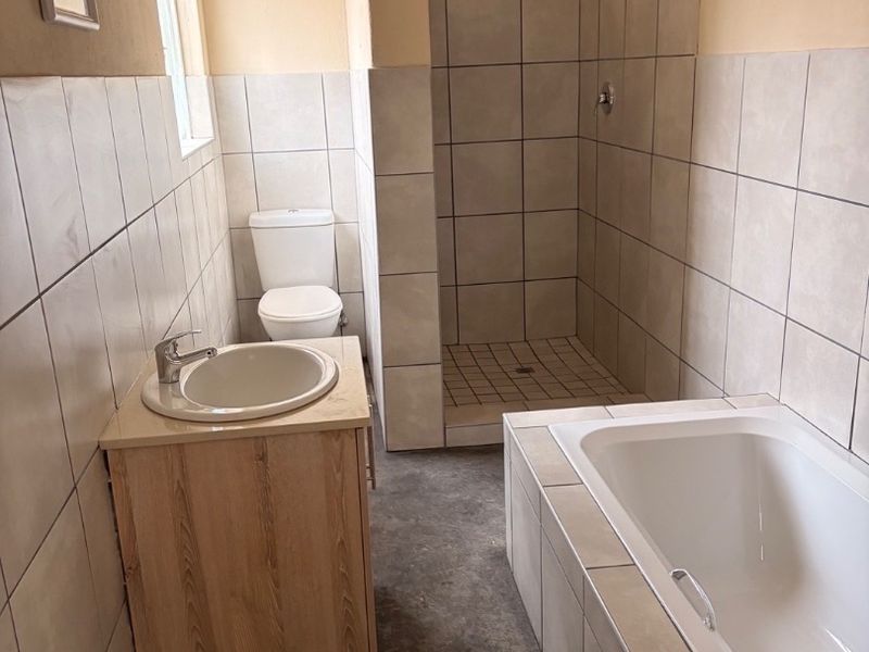 A functional bathroom featuring a built-in vanity, a separate walk-in shower, and a bathtub with neutral wall tiling.