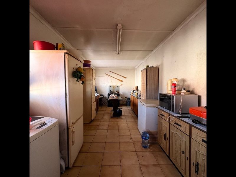 A dated kitchen featuring tiled flooring and original built-in cabinetry, requiring significant renovation to modernize the space.