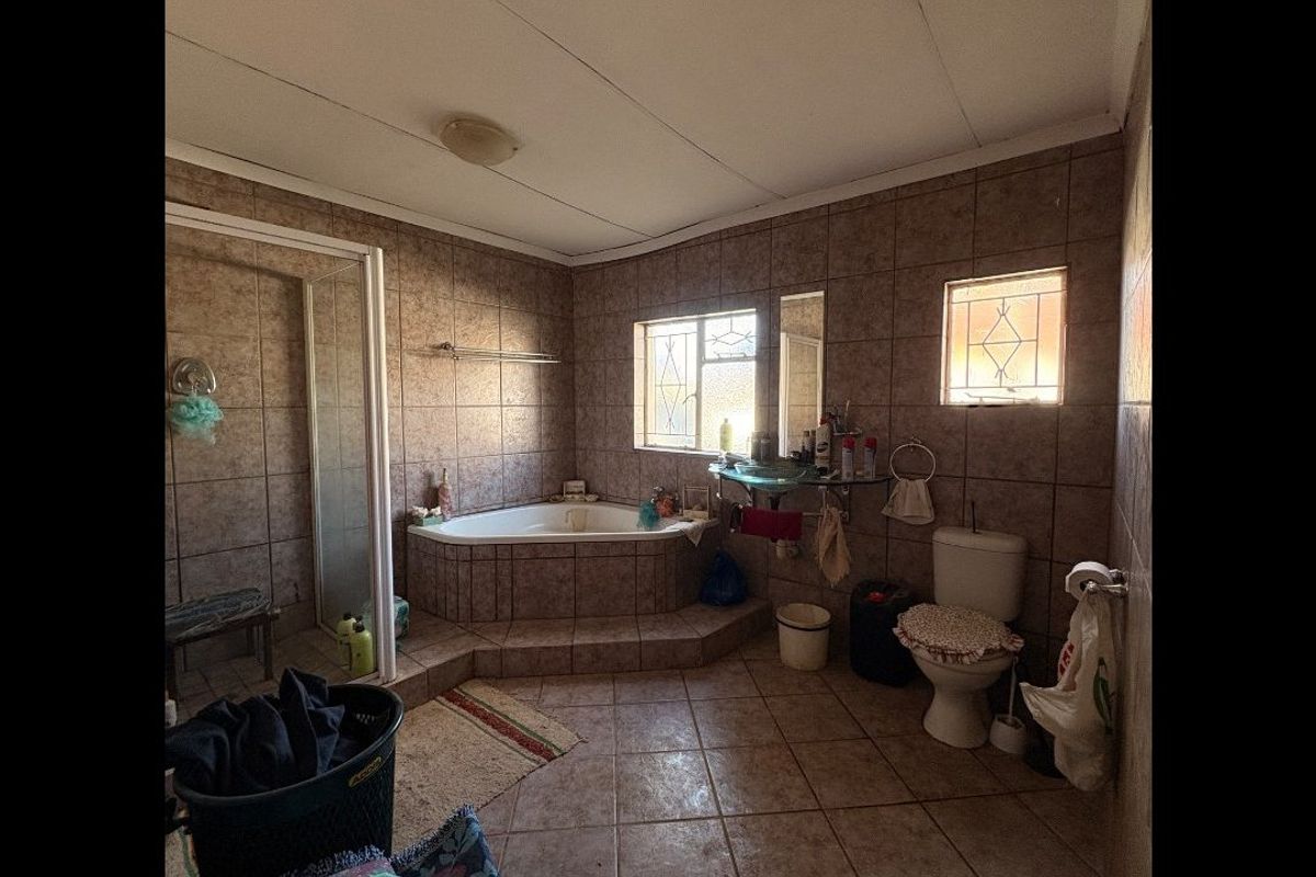 A dated bathroom featuring a corner bathtub, separate shower enclosure, and tiled finishes. The space would benefit from modern updates to fixtures and tiling.