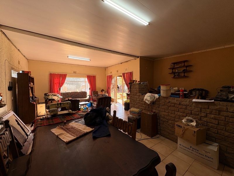 Open plan living and dining area featuring tiled floors, exposed brick accents, and direct access to the outdoor space through sliding glass doors.