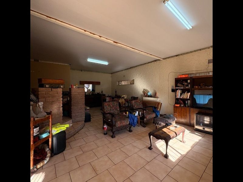 Open plan living area featuring tiled flooring and a brick fireplace, requiring cosmetic updates to the ceiling and wall finishes.