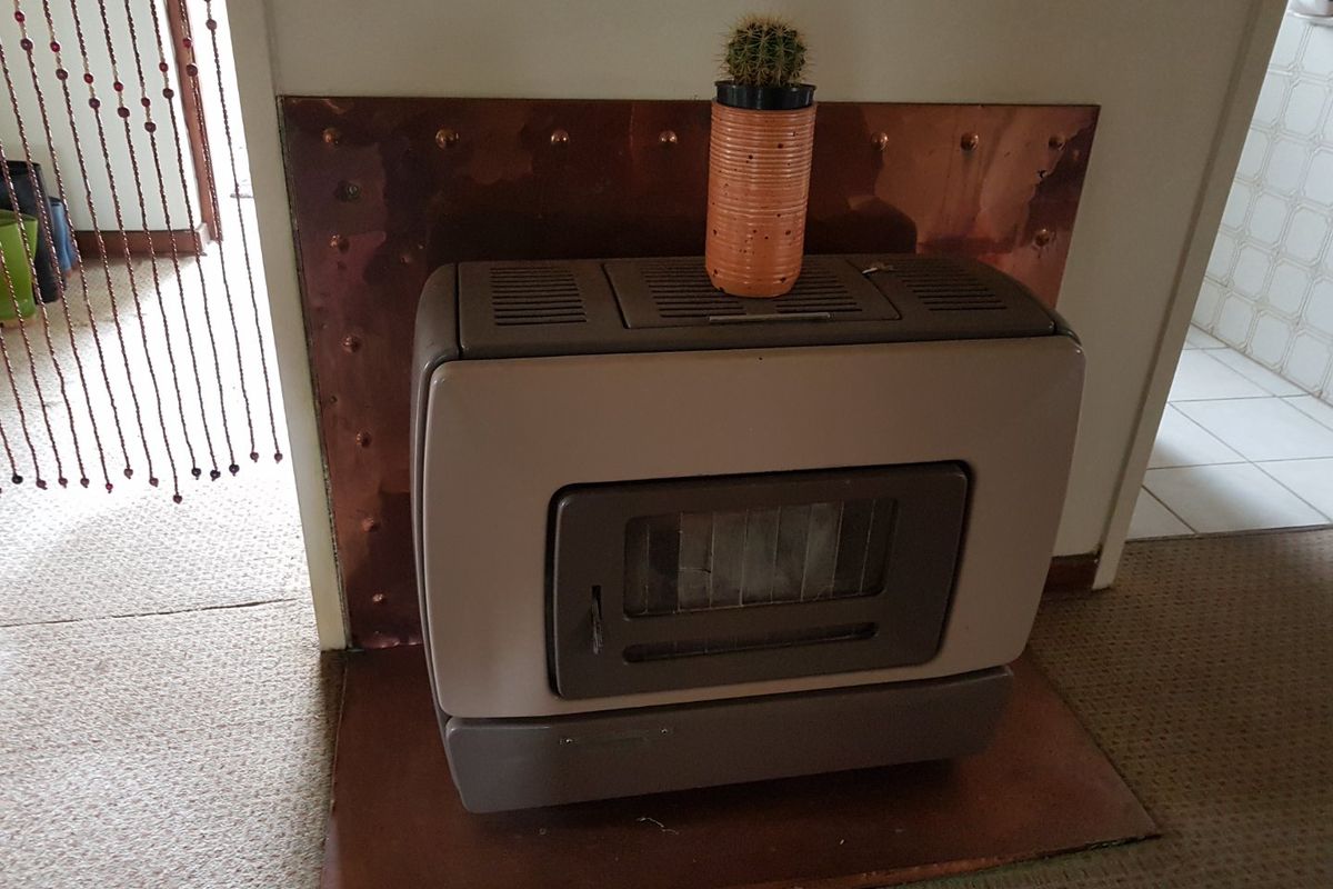 A freestanding fireplace unit set against a decorative copper wall panel and matching copper hearth in a living area.