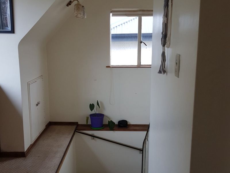 A functional hallway area featuring a staircase, sloped ceiling, and built-in storage access panel, providing access to the upper level of the home.
