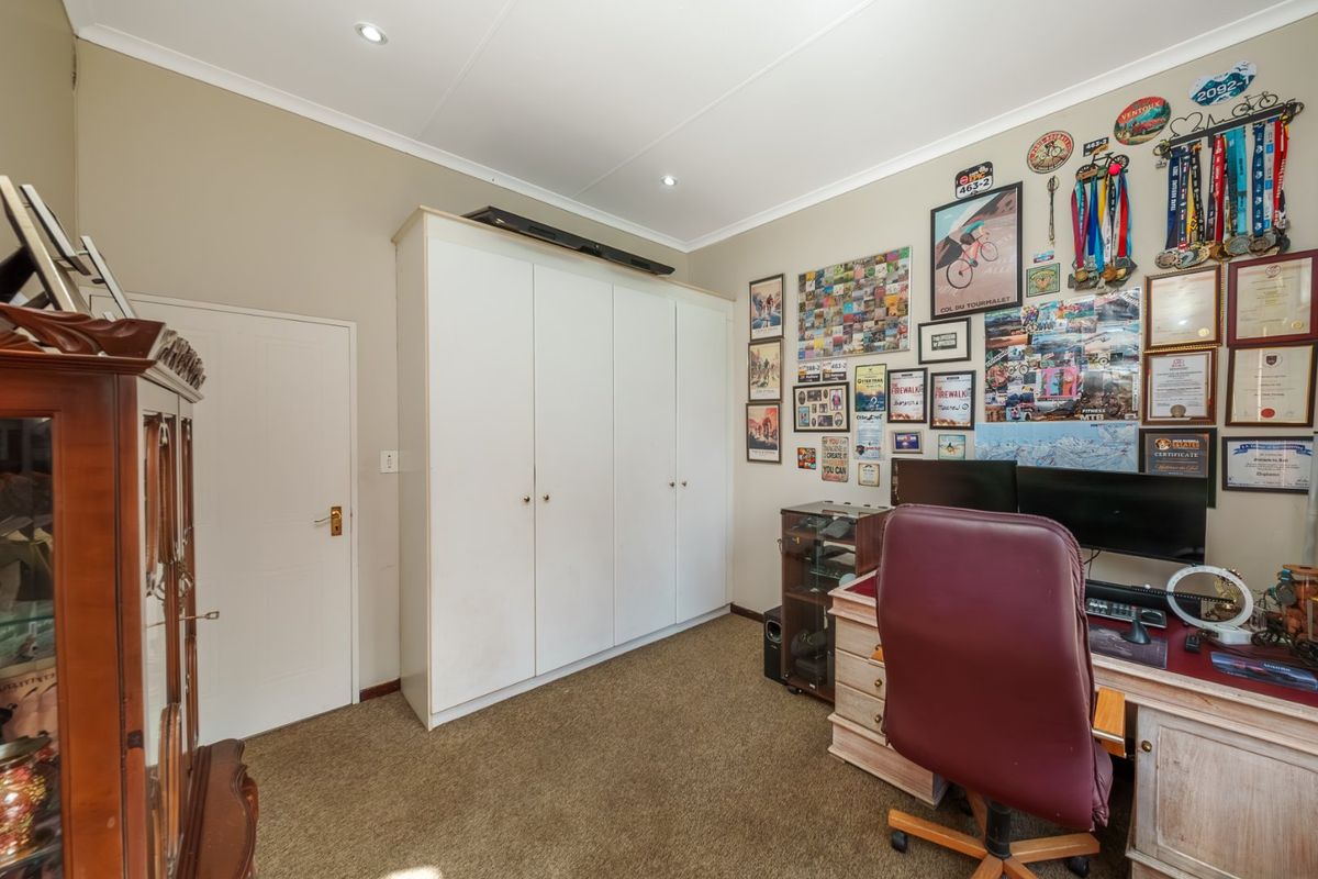 A bedroom featuring neutral walls, carpeted flooring, and a large built-in wardrobe with white cabinetry.