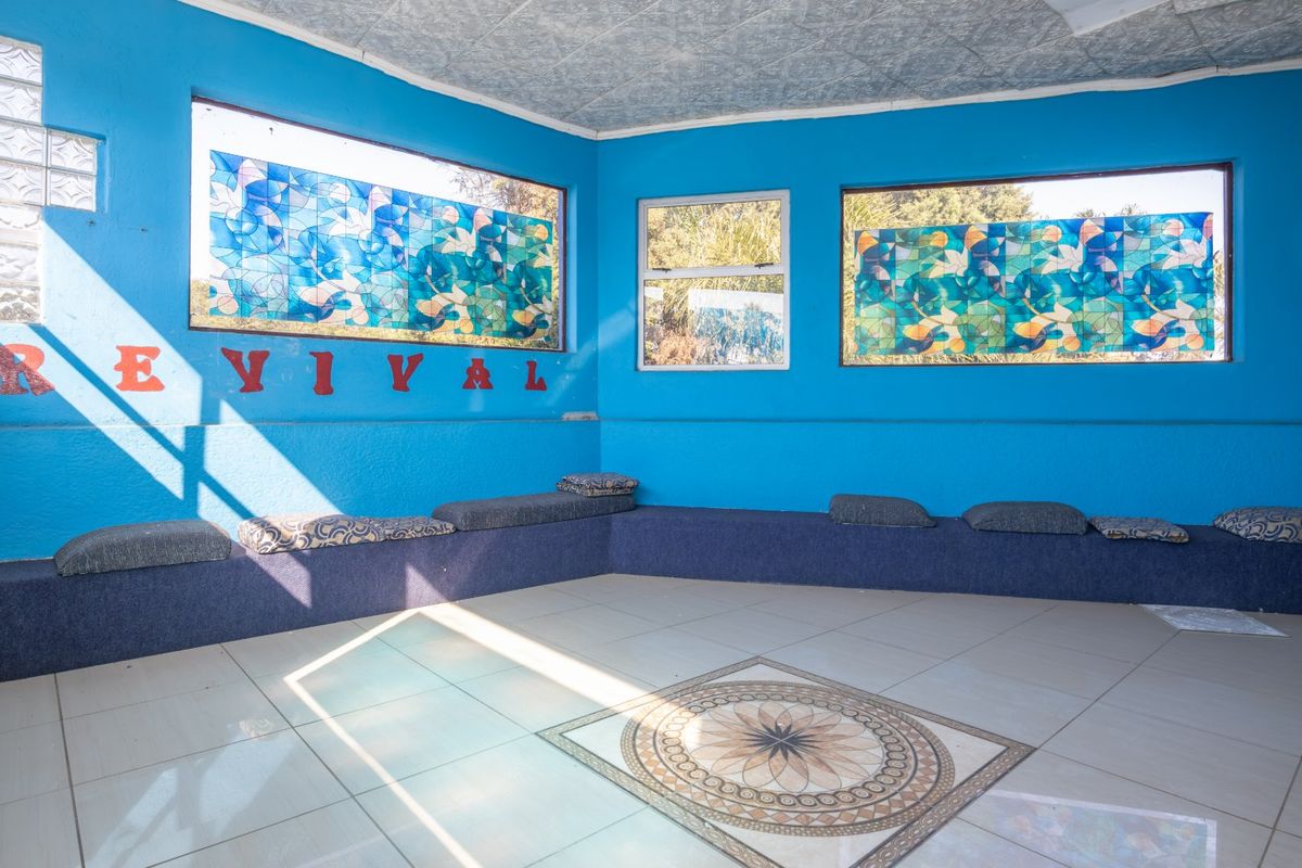 A spacious room featuring built-in seating, decorative floor tiles, and unique stained glass windows, offering a distinct layout ready for modernization.