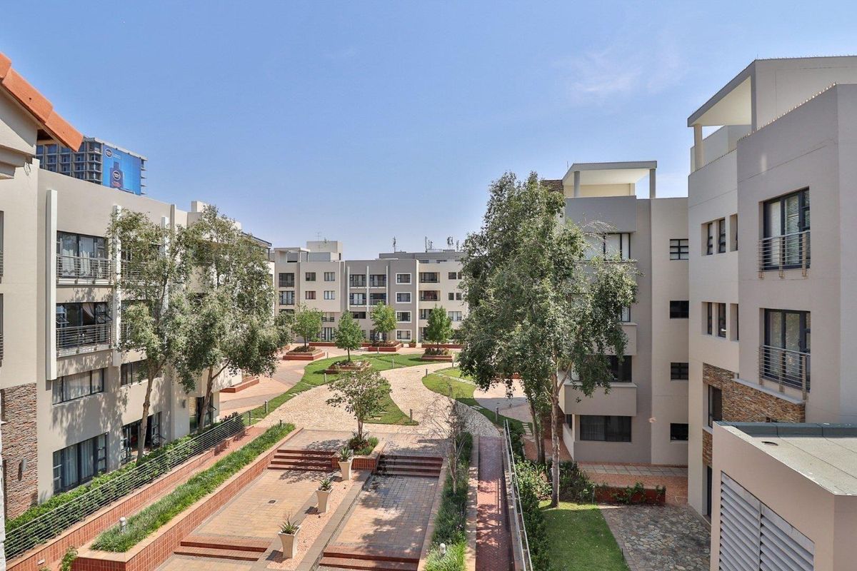 A view of the well-maintained communal courtyard and landscaped gardens situated between the apartment complex buildings.