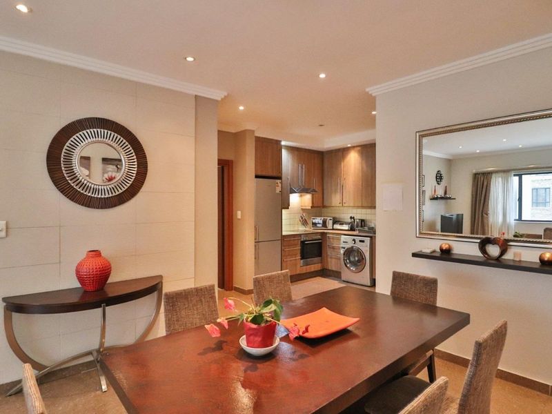 Open-plan dining area flowing into a compact, well-equipped kitchen with built-in cabinetry and integrated appliances.