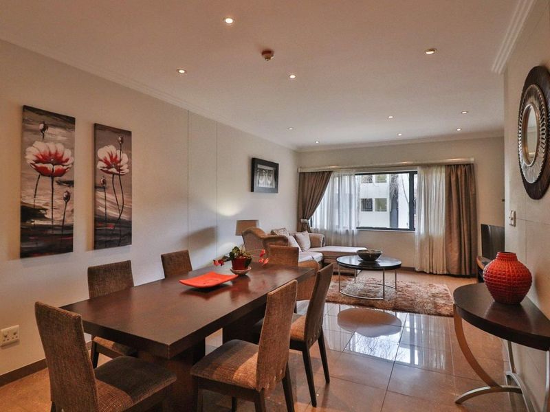 An open-plan living and dining area featuring polished tiled flooring, recessed downlighting, and coved cornicing, creating a cohesive and functional living space.