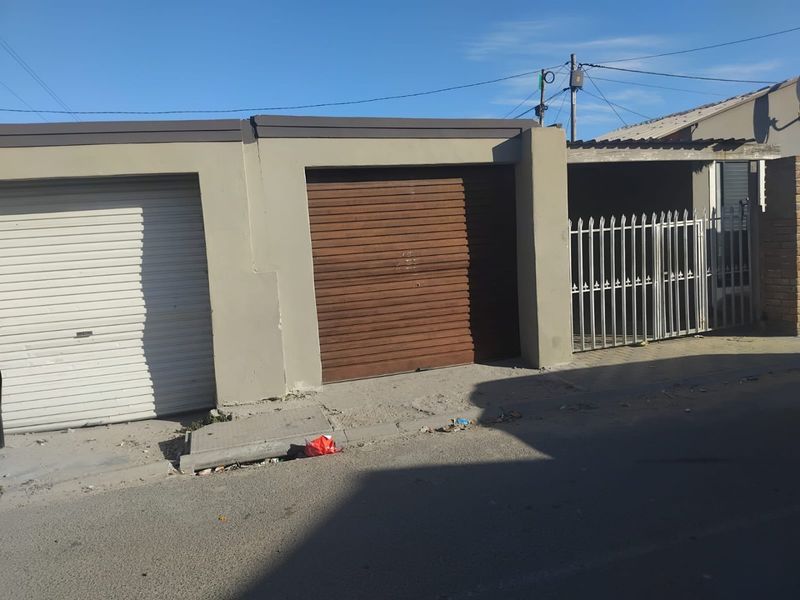 Street-facing view of a property featuring multiple roller shutter garage doors and a metal security gate entrance.