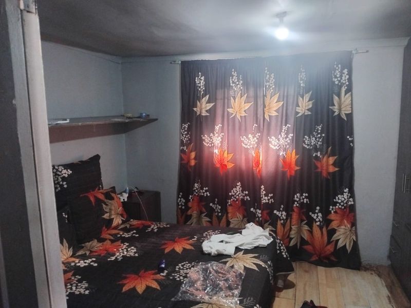 A bedroom featuring tiled flooring, built-in shelving, and a fitted wardrobe, requiring cosmetic updates to improve the overall finish and appeal.