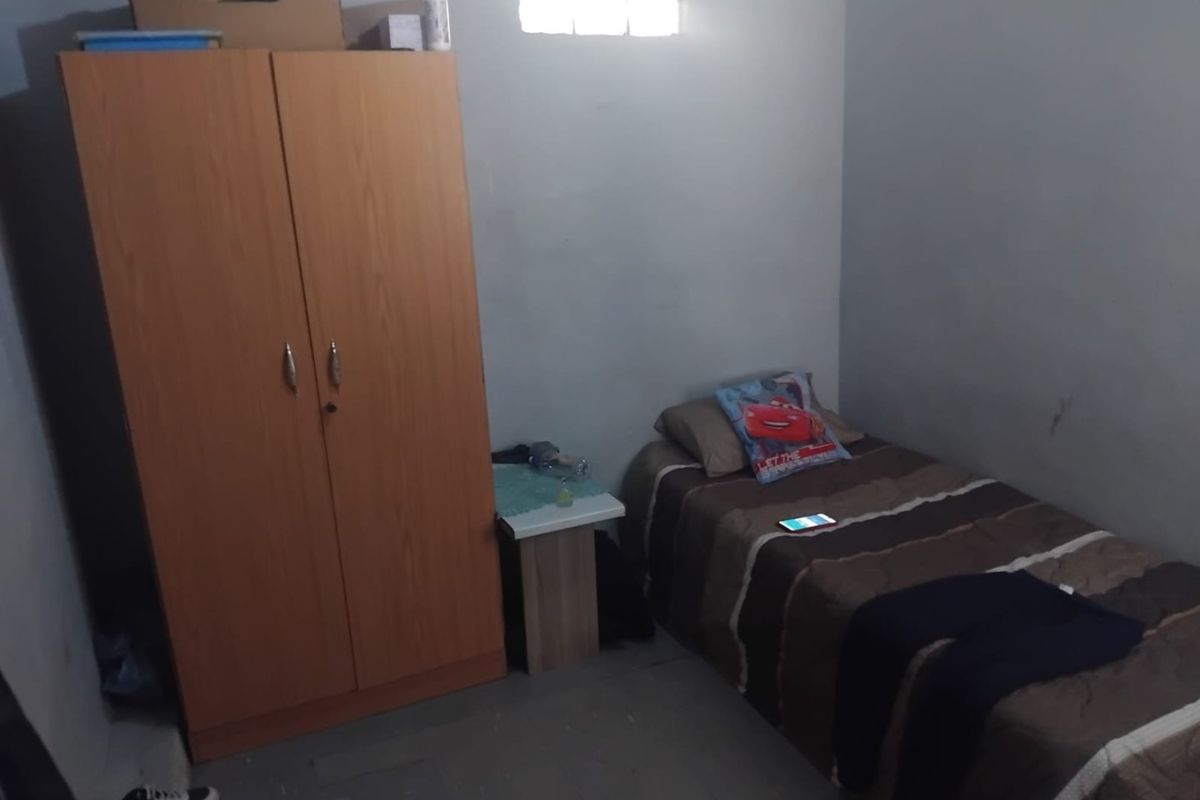 A compact bedroom featuring a high-level ventilation window and basic wall finishes, suitable for a single occupant.