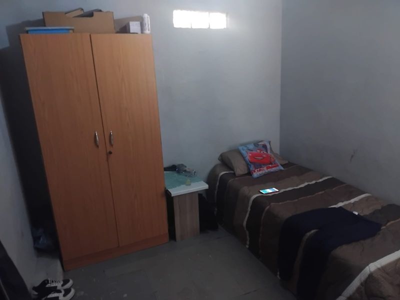 A compact bedroom featuring a high-level ventilation window and basic wall finishes, suitable for a single occupant.