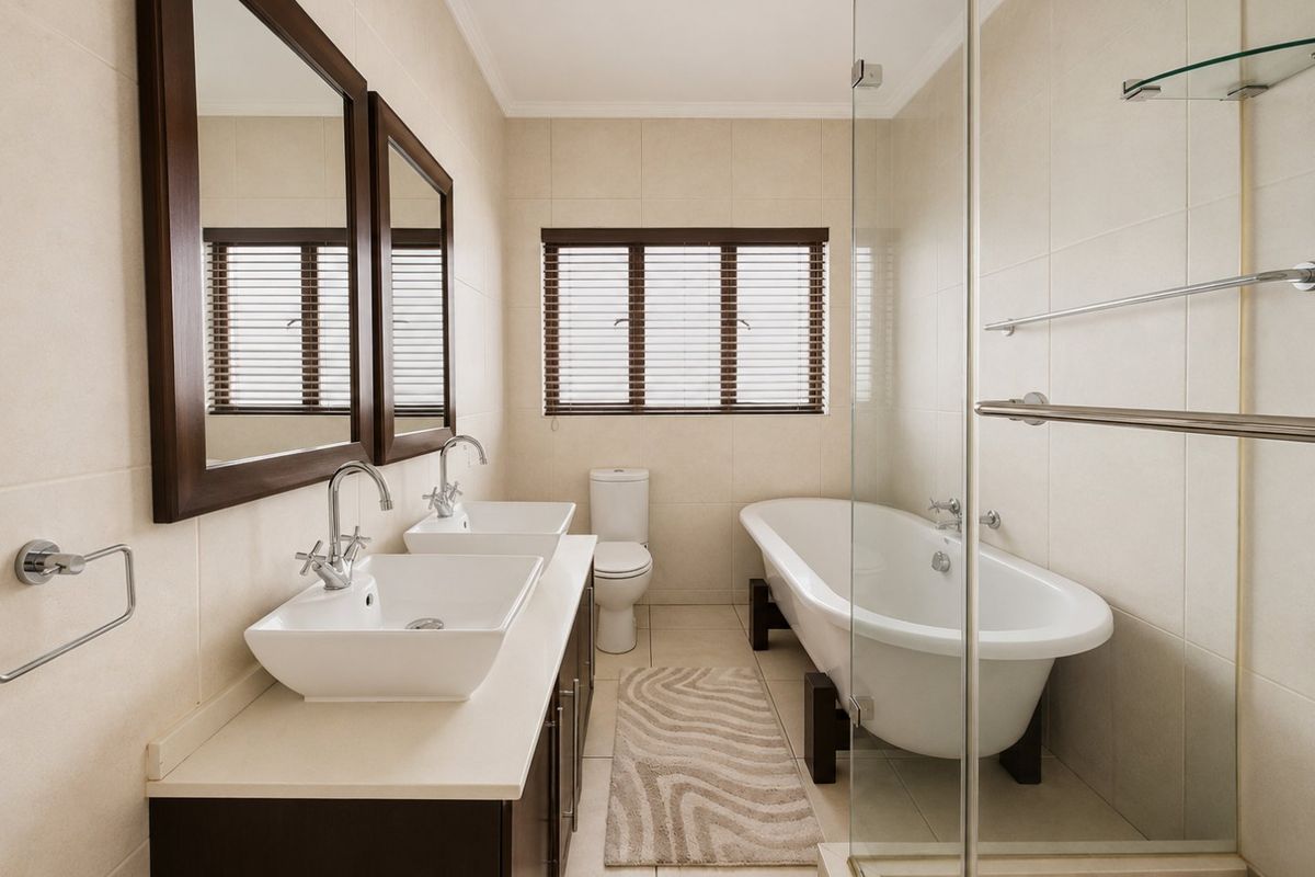 Modern bathroom featuring a double vanity with vessel sinks, a freestanding bathtub, a glass-enclosed shower, and neutral wall and floor tiling.