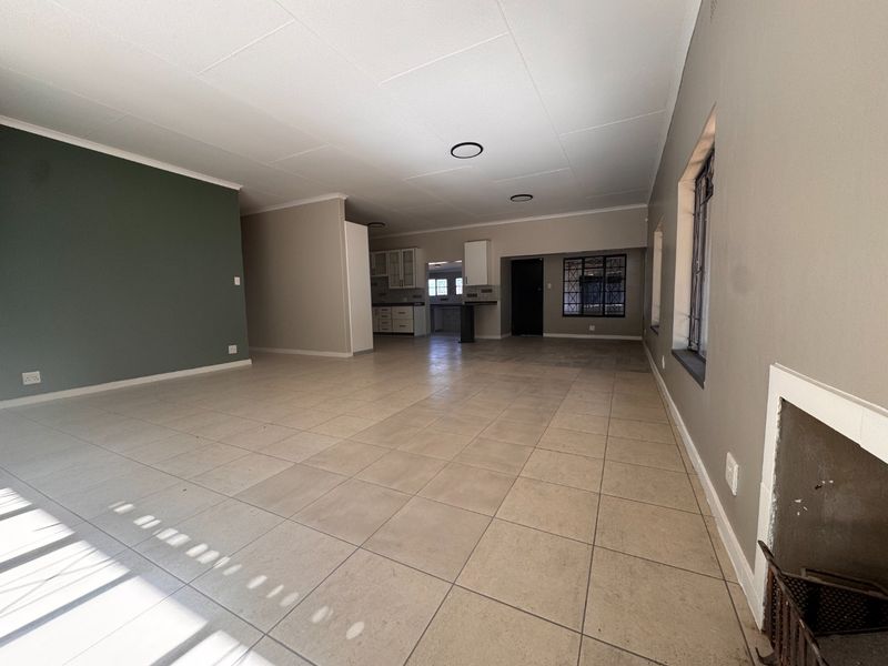Spacious open-plan living area featuring tiled floors, a built-in fireplace, and a view through to the kitchen area.