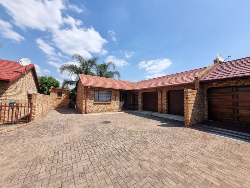 A well-maintained face brick house featuring a spacious paved driveway and a triple garage with secure access.