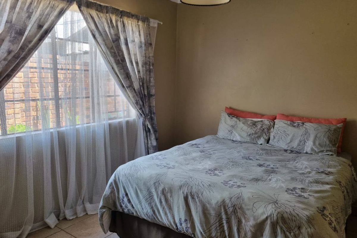 A functional bedroom featuring tiled flooring and natural light through a window with curtain rails.