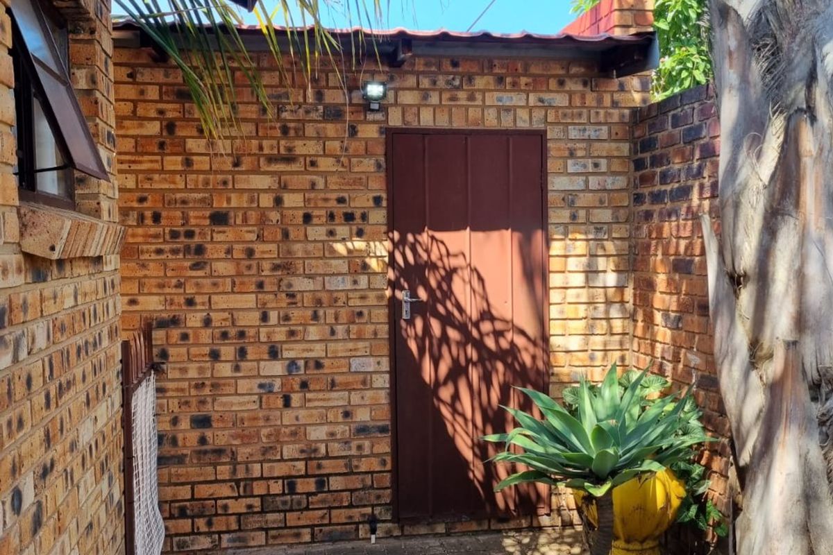 A private rear courtyard area featuring face brick walls, paved flooring, and a secure metal access door.