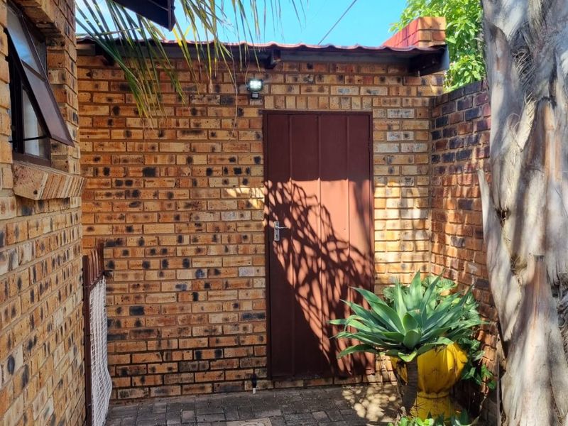 A private rear courtyard area featuring face brick walls, paved flooring, and a secure metal access door.
