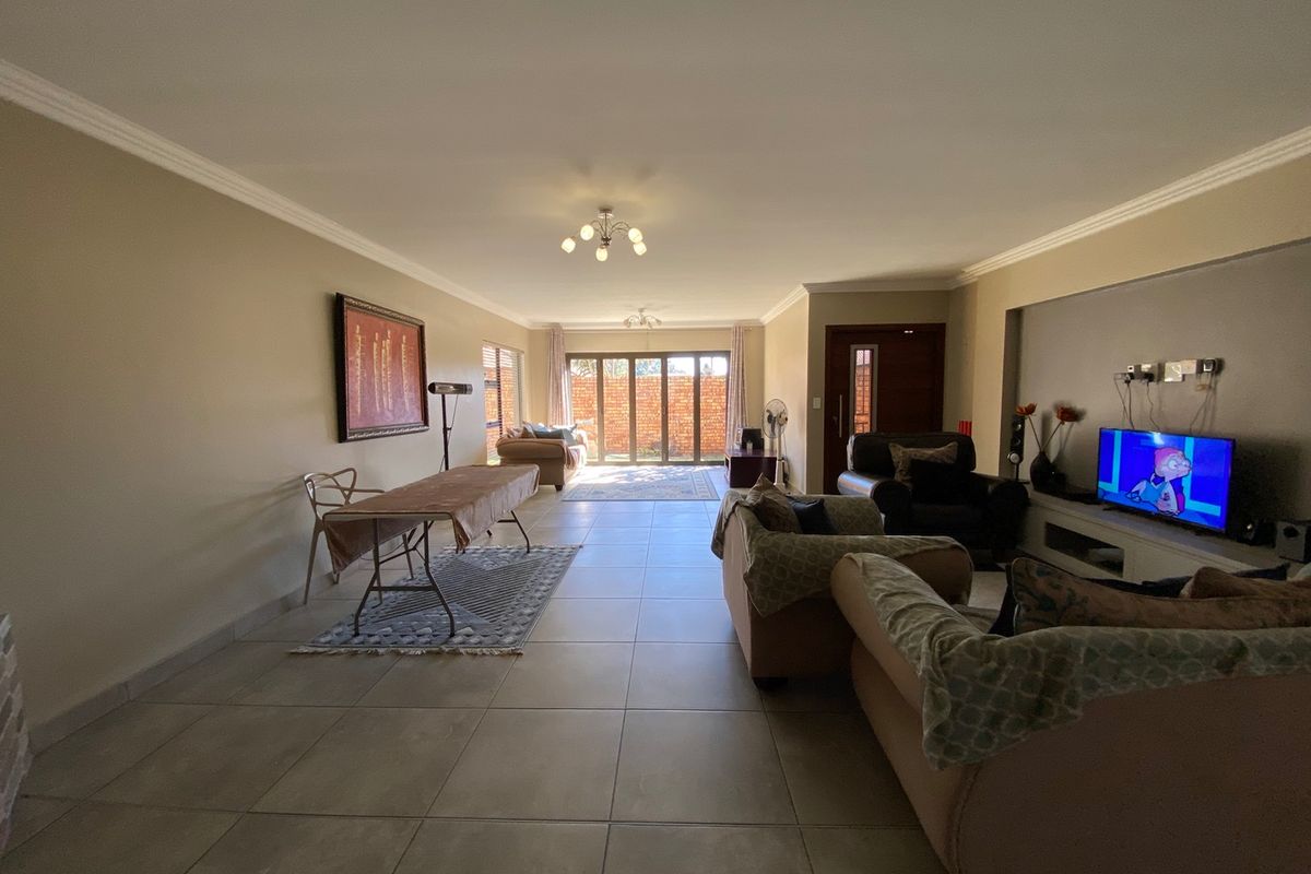 Spacious open-plan living area featuring large format floor tiles, built-in media cabinetry, and sliding glass doors leading to the rear outdoor space.