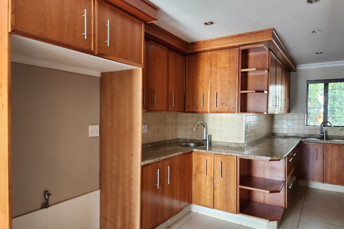 A functional kitchen featuring wooden cabinetry, granite countertops, tiled backsplash, and recessed lighting, offering a clean and practical workspace.