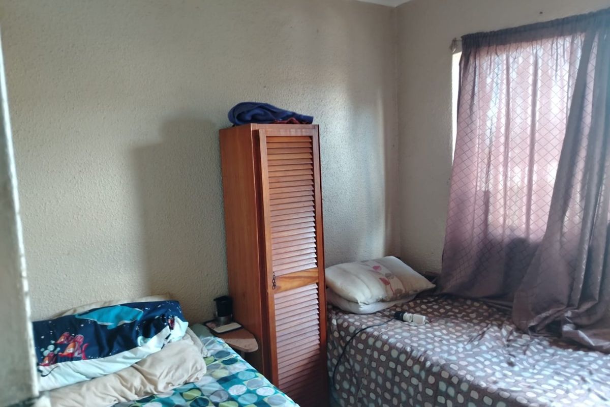 A compact bedroom featuring a window with curtains and textured wall finishes, suitable for a single occupant or child's room.