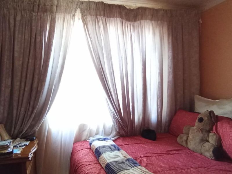 A bedroom featuring a window with curtains, providing natural light to the space.