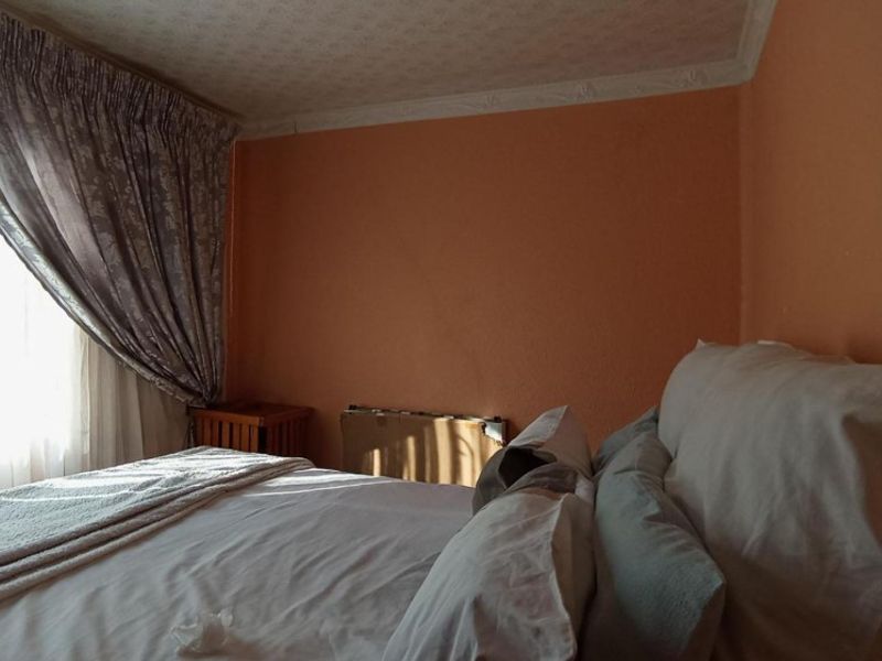 A bedroom featuring a radiator and decorative coving, currently finished with peach-toned walls.