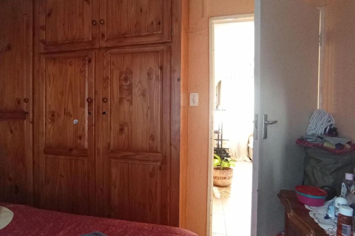 Bedroom featuring built-in wooden cupboards and a doorway leading to an adjacent living space.