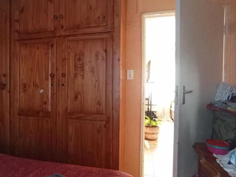 Bedroom featuring built-in wooden cupboards and a doorway leading to an adjacent living space.