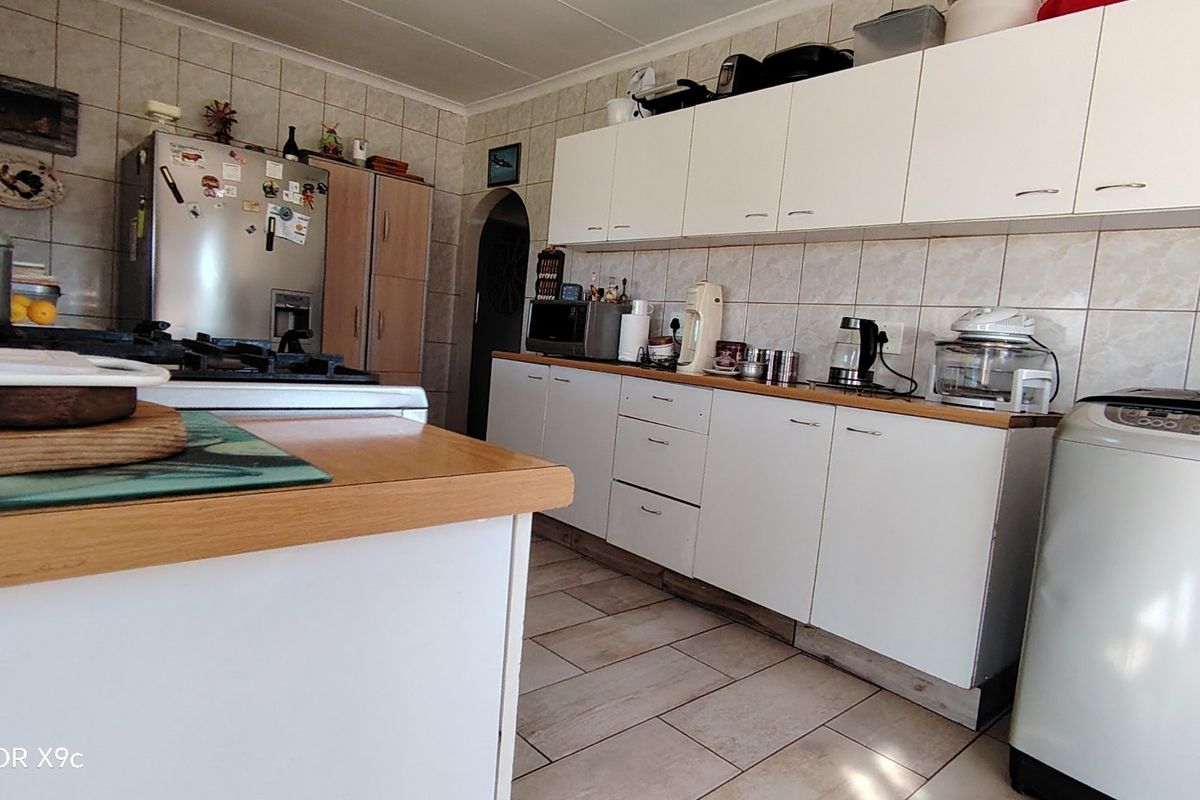 A functional kitchen featuring white cabinetry, tiled backsplash, and tiled flooring, providing a practical workspace with integrated cooking appliances.