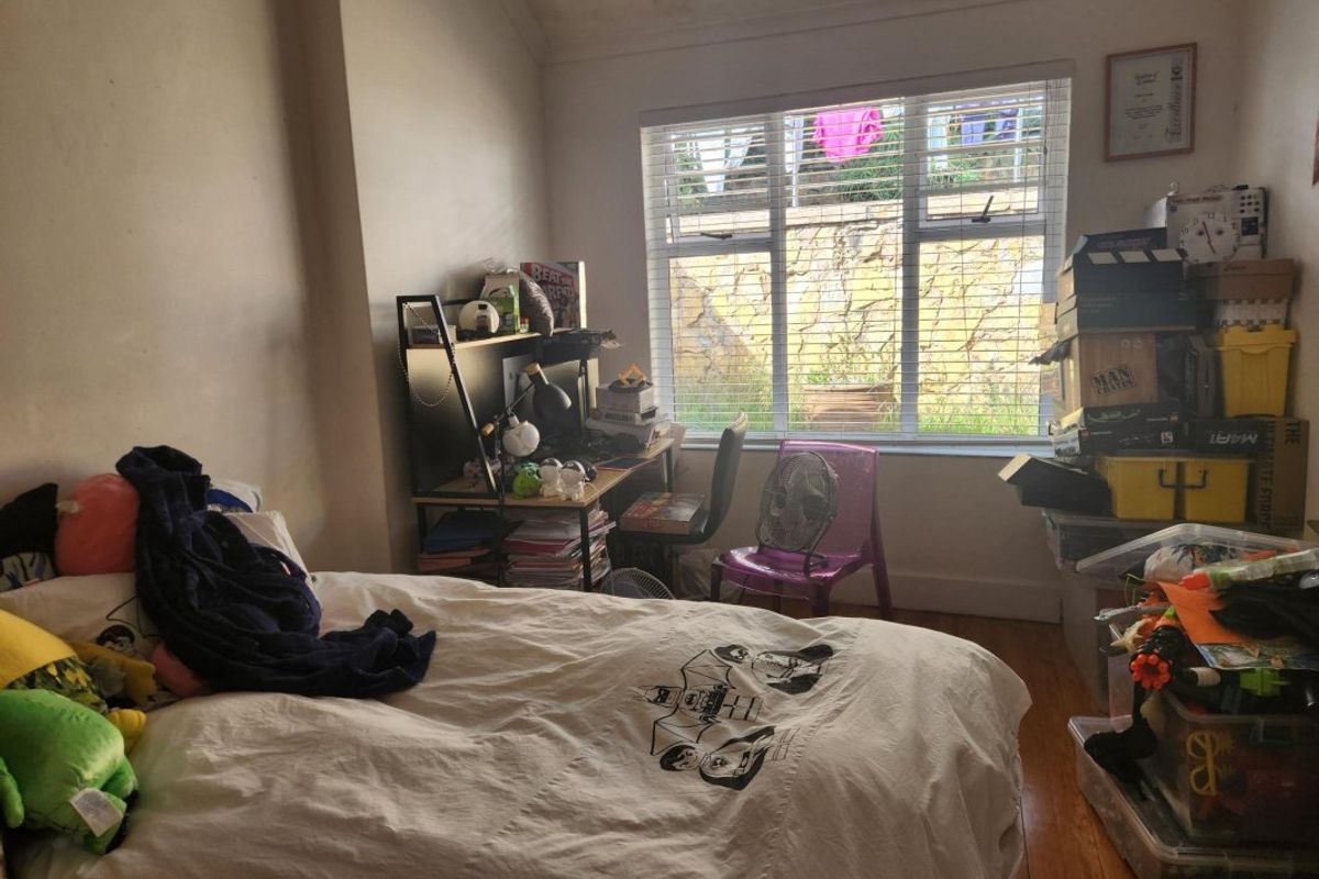 A bedroom featuring hardwood flooring and venetian blinds, currently requiring cosmetic updates to the walls and ceiling to improve its overall appeal.