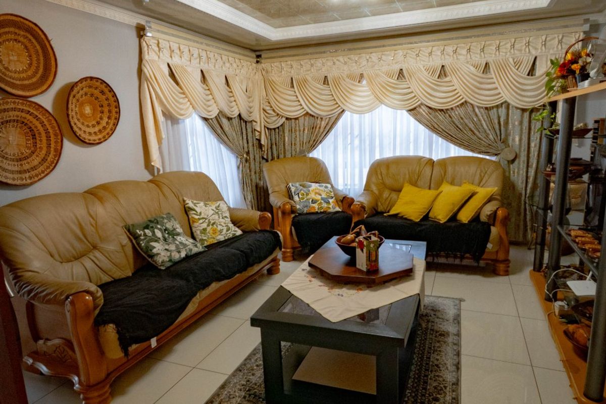 A living room featuring polished floor tiles, decorative ceiling panels, and crown molding, providing a traditional foundation for updated interior styling.