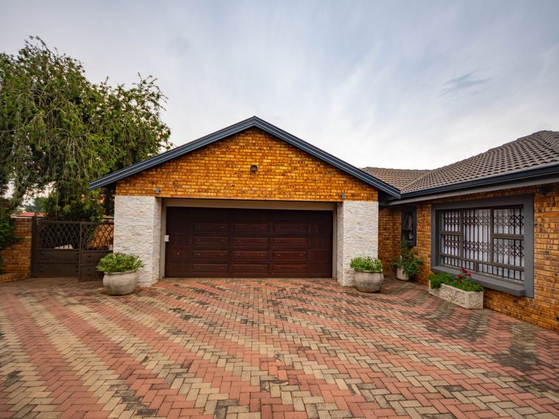 Front exterior view of the property featuring a paved driveway, facebrick facade, and a double garage with a tiled roof.