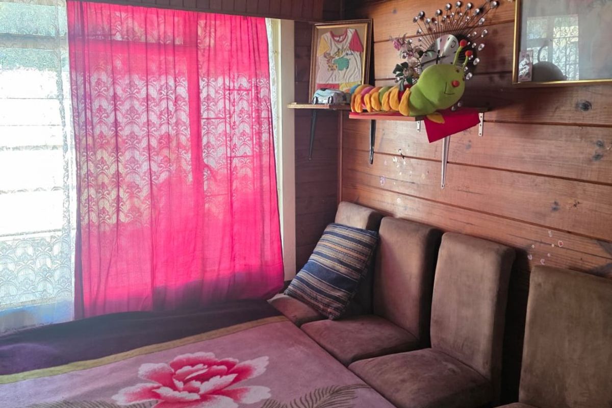 Bedroom featuring timber wall paneling and a textured ceiling, offering a rustic aesthetic that could be updated with modern finishes.