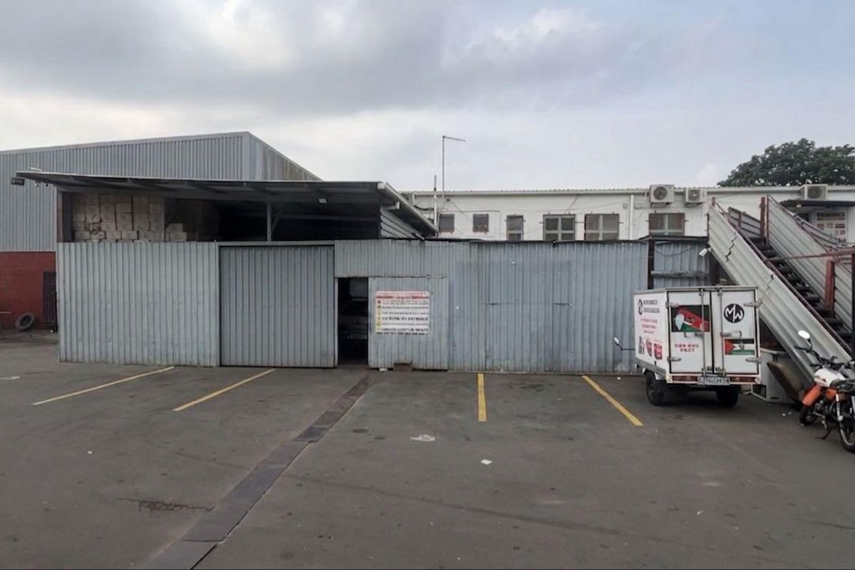 Industrial property exterior featuring corrugated metal cladding, a large sliding access door, external staircase, and an asphalt-paved parking area.