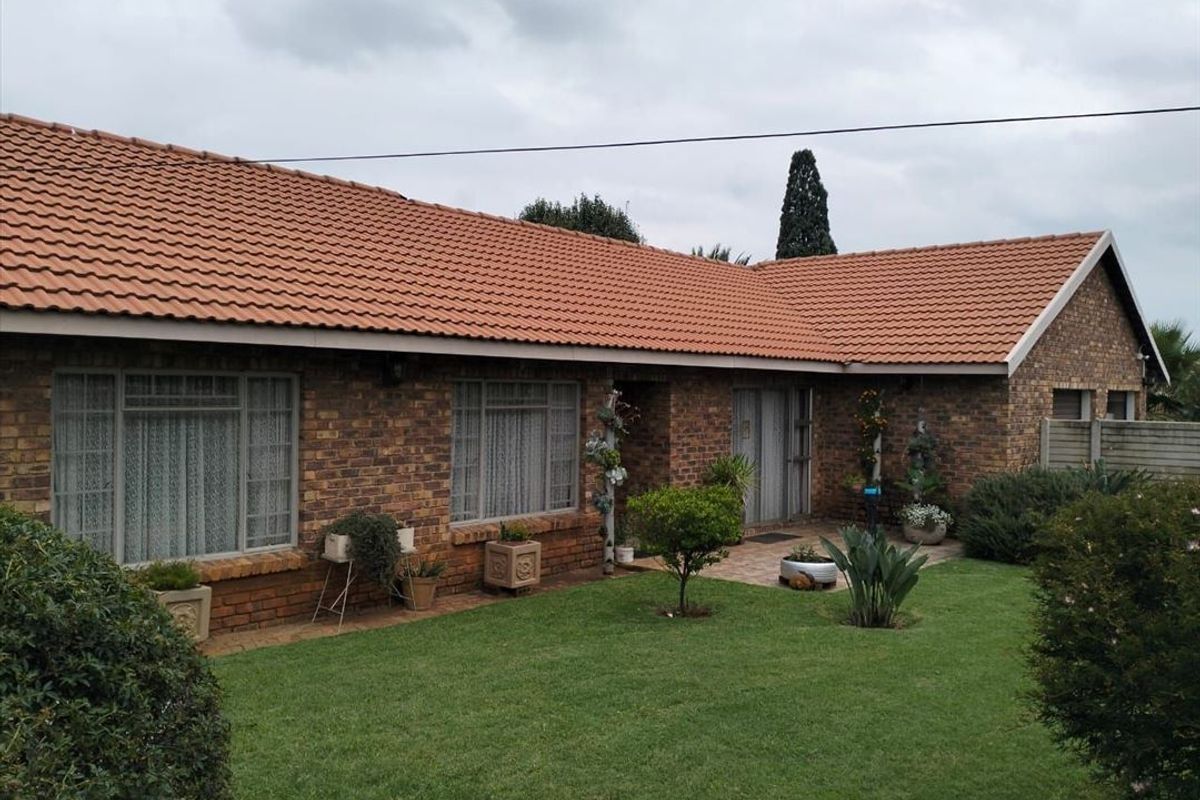 A well-maintained single-story home featuring a classic face brick exterior, terracotta tiled roof, and a neat garden with a paved patio area.