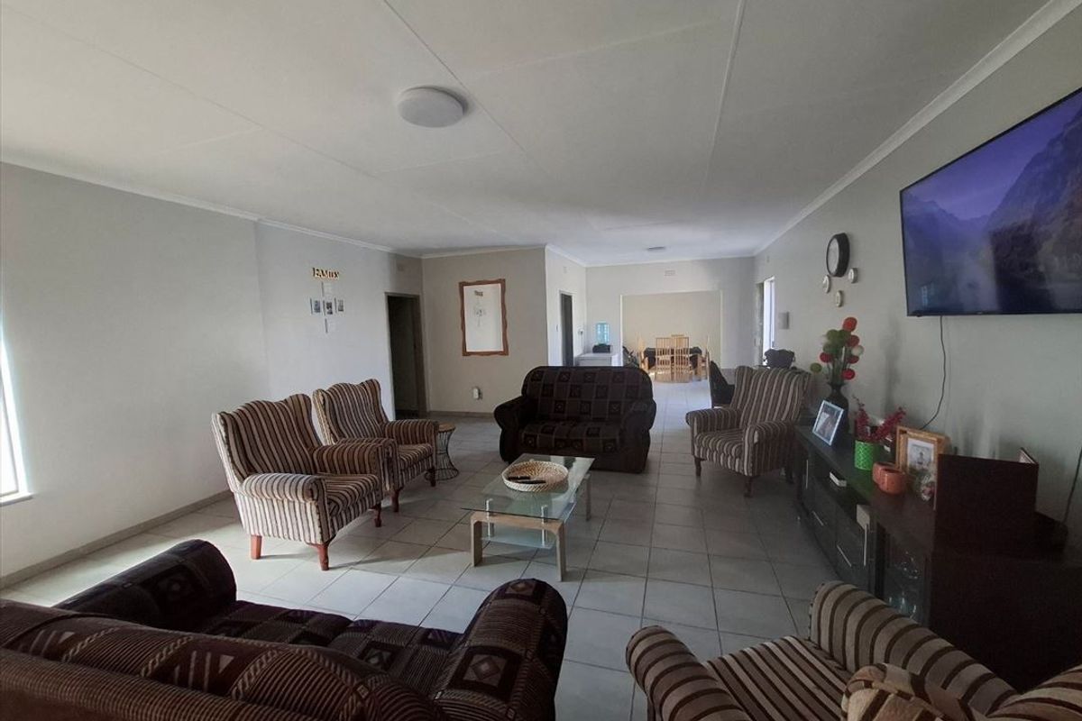 Spacious living room featuring neutral tiled flooring and coved ceilings, providing a comfortable and open area for family relaxation.