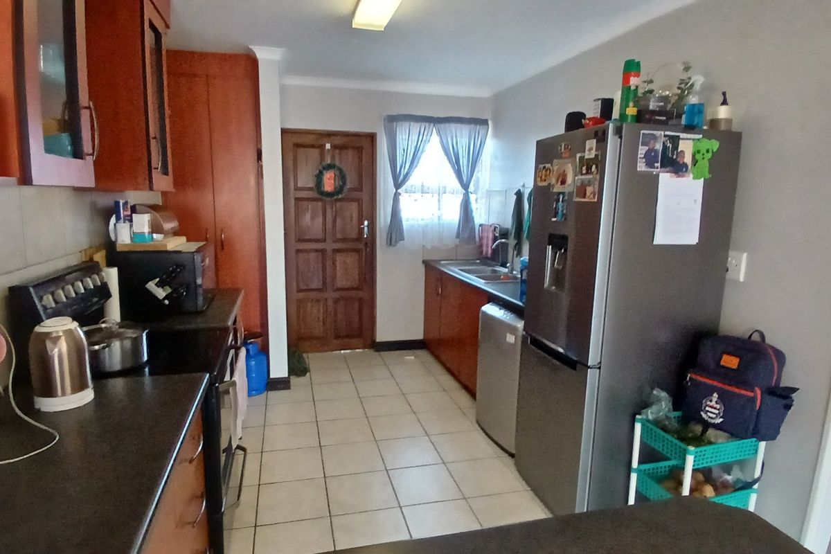 A functional kitchen featuring tiled flooring, built-in cabinetry, laminate countertops, and a double basin sink, with direct access to an exterior door.