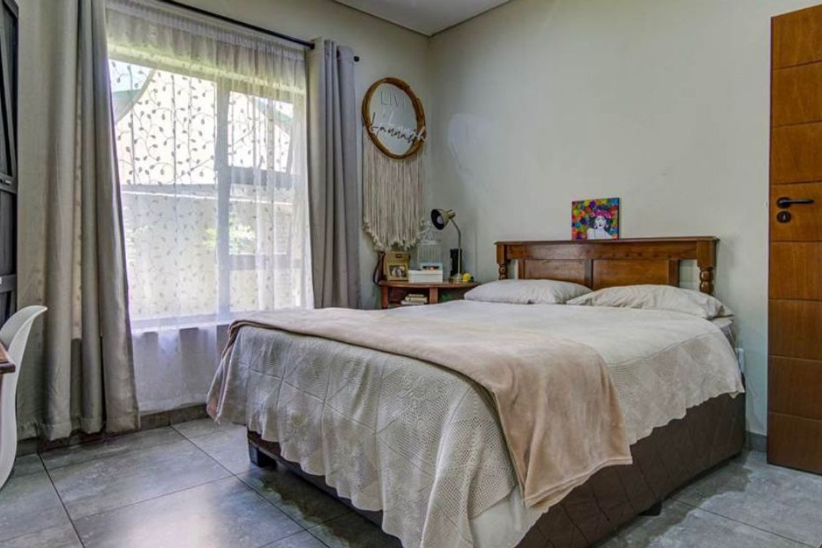 A well-maintained bedroom featuring tiled flooring, a wooden door, and natural light from a large window.
