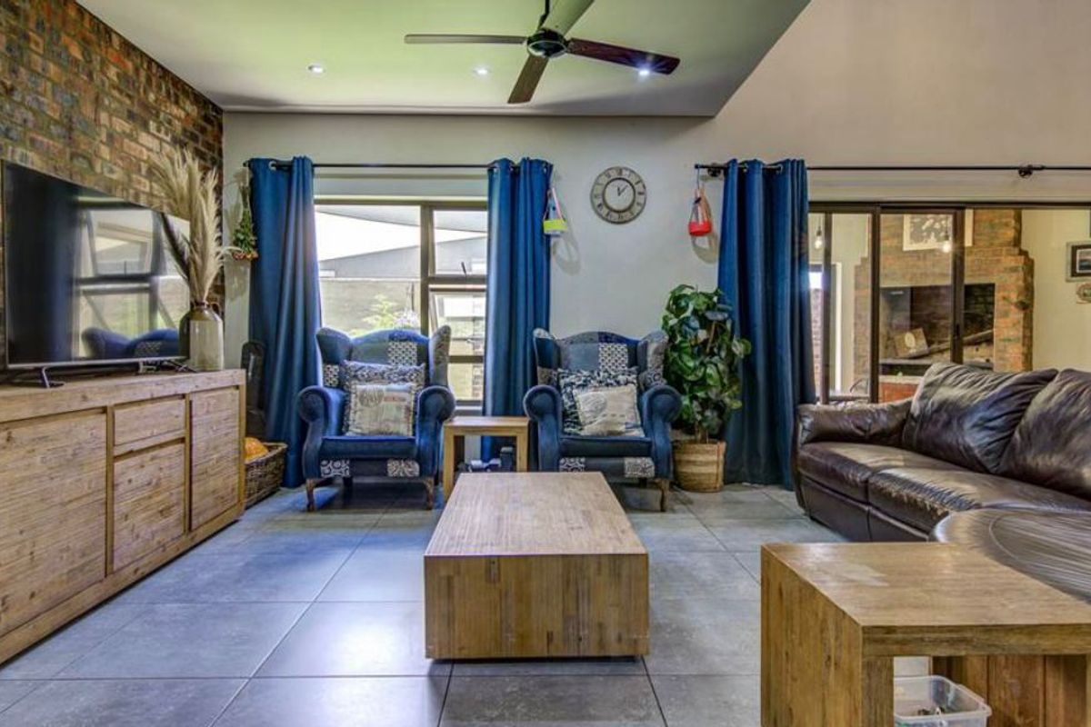Spacious living room featuring an exposed brick feature wall, large format floor tiles, and sliding glass doors leading to an outdoor area.