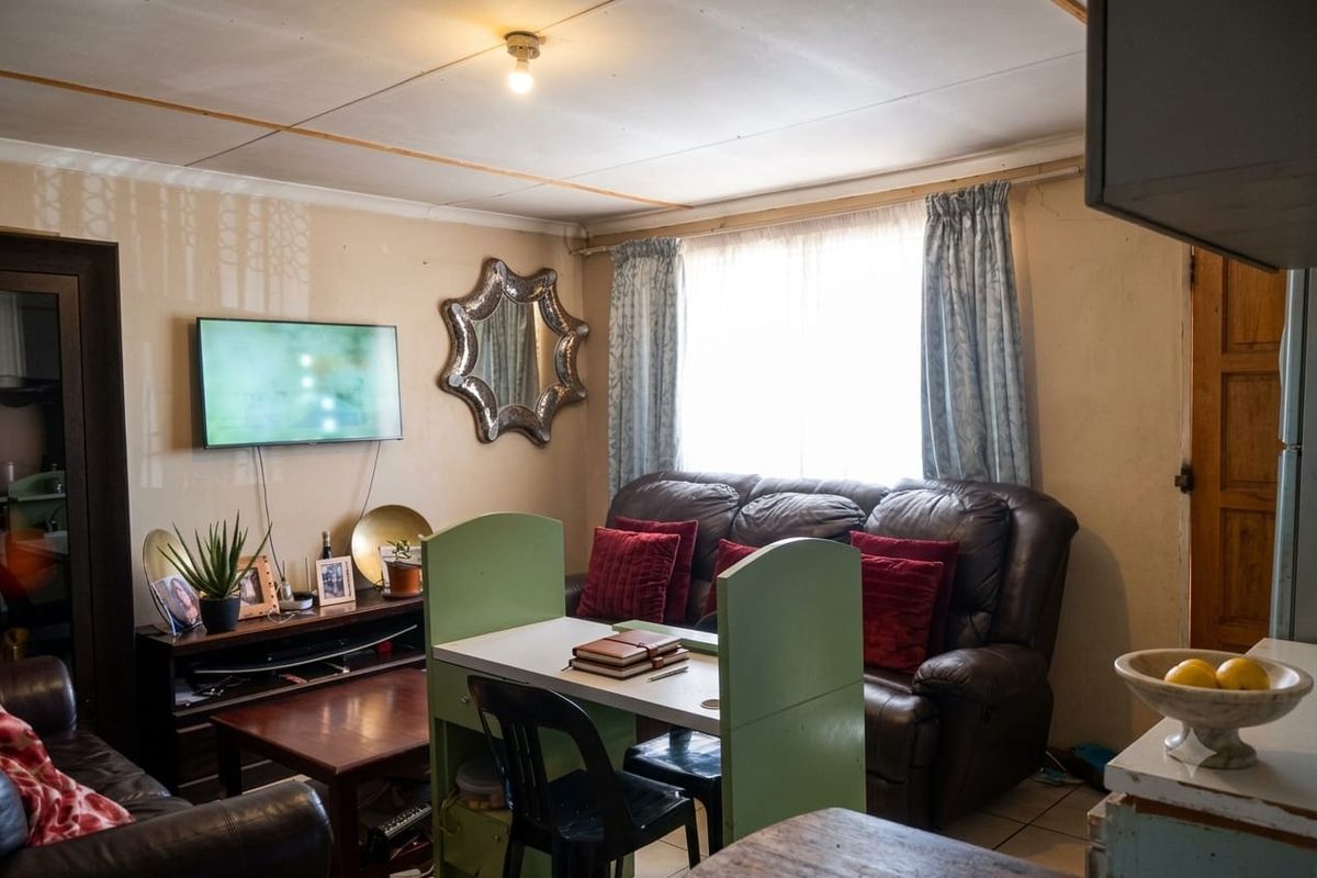 A living room area featuring tiled flooring and standard ceiling finishes, currently utilized as a combined lounge and dining space.