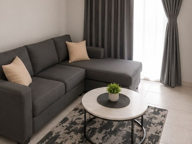 A well-lit living room area featuring neutral tiled flooring and floor-to-ceiling curtains, providing a clean and modern foundation for the space.