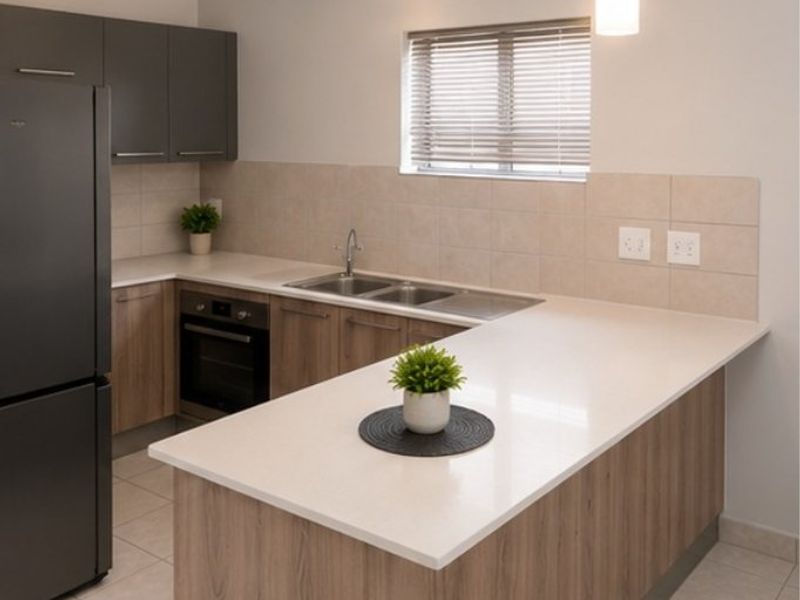 Modern kitchen featuring wood-finish cabinetry, stone countertops, a double sink, built-in oven, and a functional breakfast bar layout.