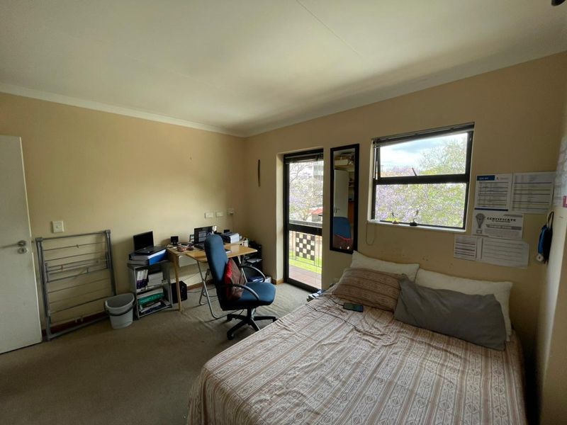 A bedroom featuring carpeted flooring, a sliding glass door leading to a balcony, and a window providing natural light.