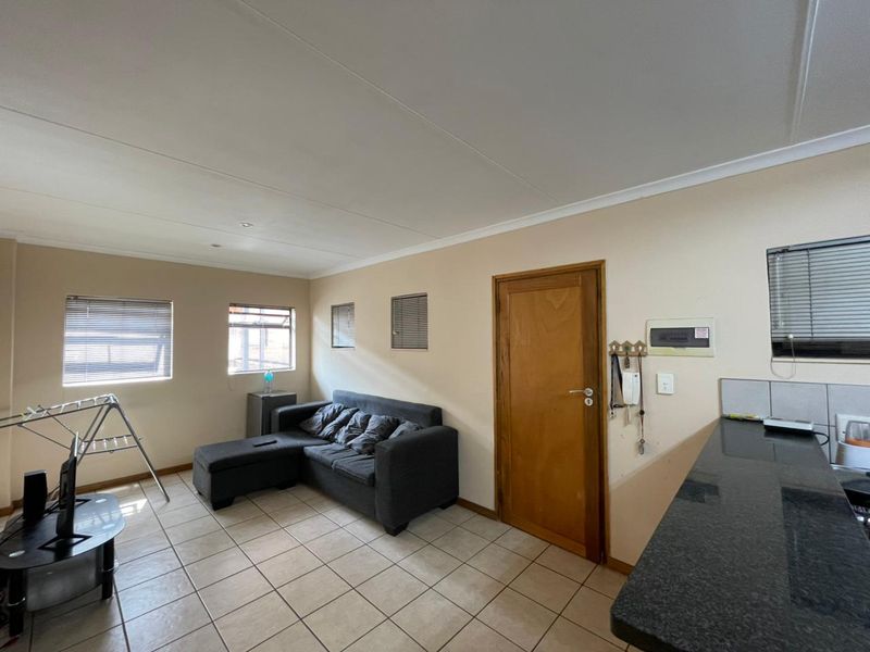 Open-plan living area featuring tiled flooring, granite kitchen countertops, and multiple windows with venetian blinds, offering a functional and versatile living space.